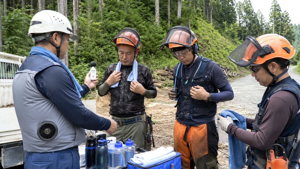 林業現場で下刈り作業前に熱中症対策用品を確認する作業者のイメージ
